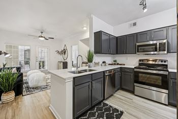 A modern kitchen with black cabinets and stainless steel appliances.